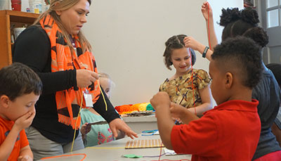 Student teacher working with a group of young children on an art project.