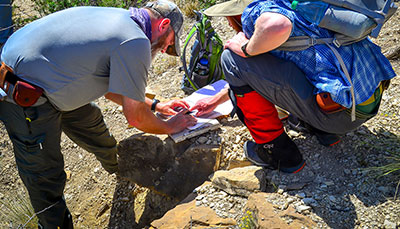 Couple people with hiking equipment looking over a map.  