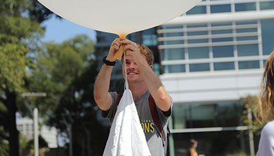 Student holding a large weather balloon ready to release it into the air.