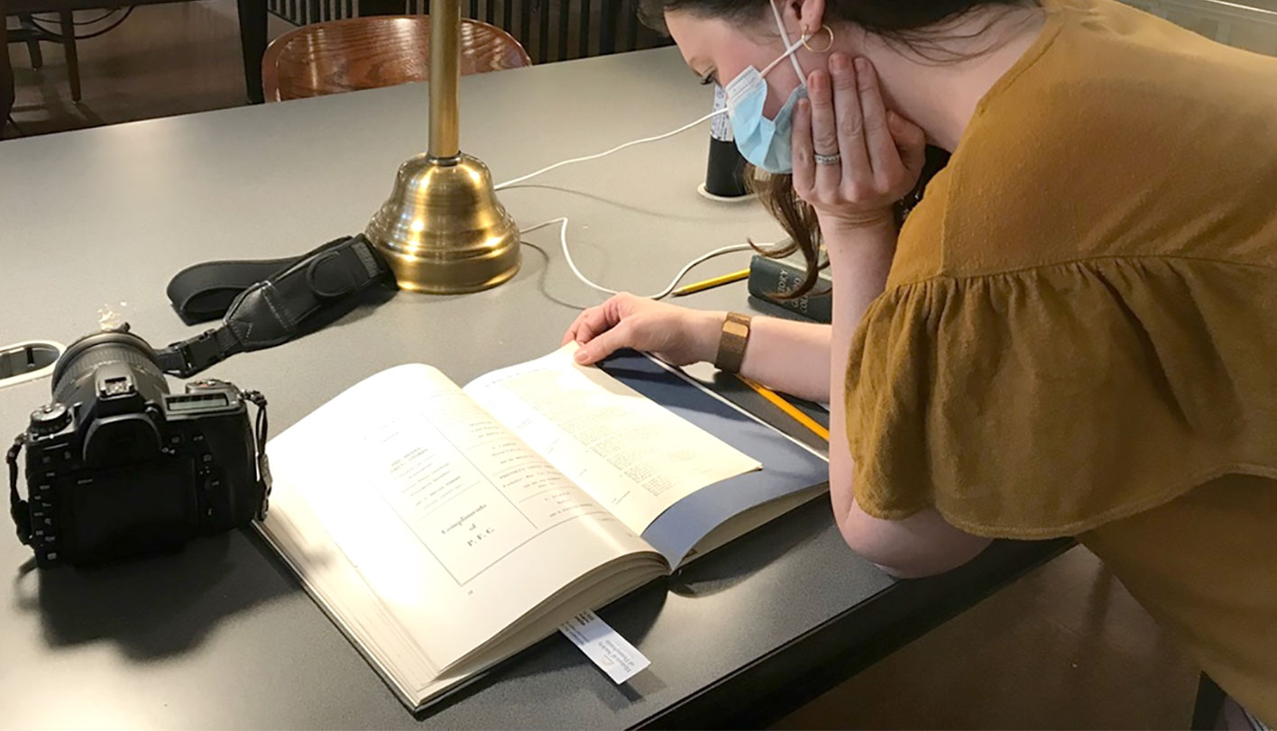 Person leaning over a table looking at a book.