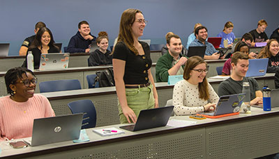 Student standing in a full classroom. 