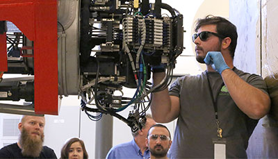 Student working on a machine with others watching on.