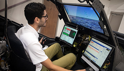 Student sitting inside a simulation machine.