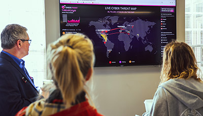 Three people looking at an infographic on a digital display.