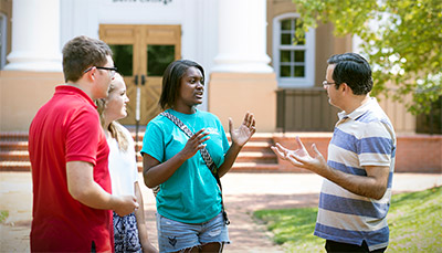 Students and teacher talking outdoors.