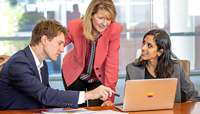 Professor talking with students at a laptop.