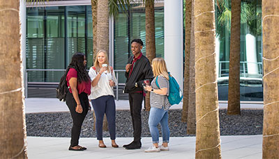 Group of business student standing outside in the Moore School courtyard.