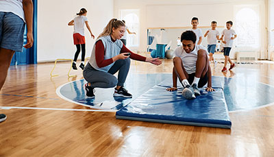 Teacher working with a student in a school gym.