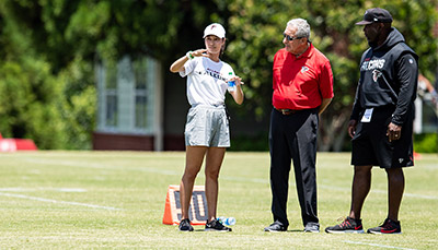 HRSM Alumni standing of a football field talking with athletic coaches.