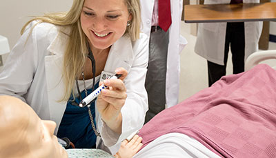 Nursing student shining a light in a patient's eyes.