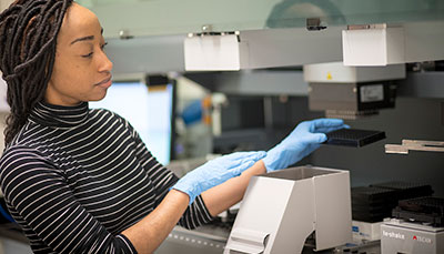 Researcher woking in a lab with a tray of test tubes. 