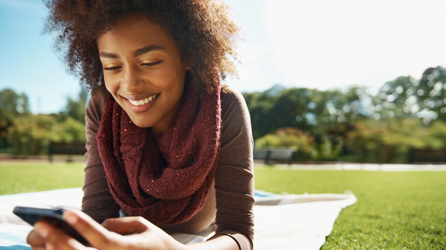 A woman smiling while looking at her cell phone