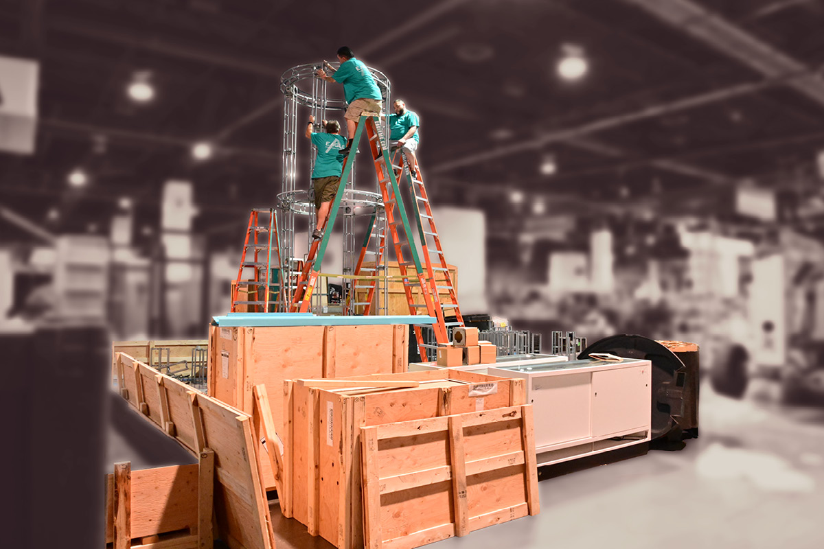 Booth under construction. Boxes, tools and a ladder appear disordered.