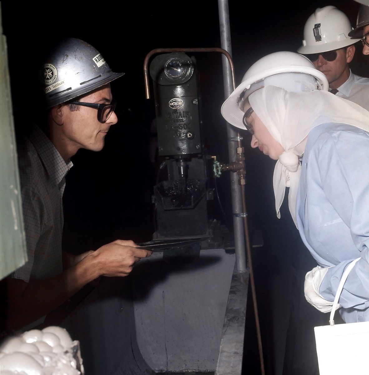 Her Majesty Queen Elizabeth II inspects an assay sample of flotation froth with Control Metallurgist Herman Dobrowolska explaining its characteristics.