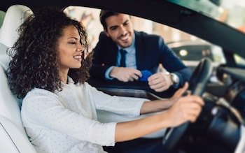 Smiling woman in the showroom enjoying luxury car