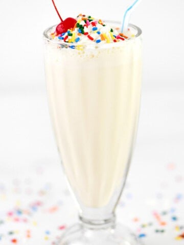 A tall glass with a milkshake inside.