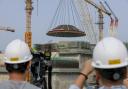 A 550-ton outer dome is hoisted into place at the construction site of the world's first commercial small modular reactor, Linglong One in China