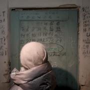 YAHIDNE, UKRAINE - JANUARY 17, 2024 - A woman faces the door with the calendar and names of the people who died in the basement of the school where Russian occupiers held more than 300 residents, including 77 children