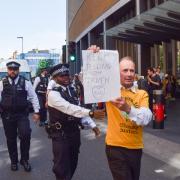 A protester holding a 'Keep telling the truth' placard blocks the traffic ahead of a van carrying jailed activists in London