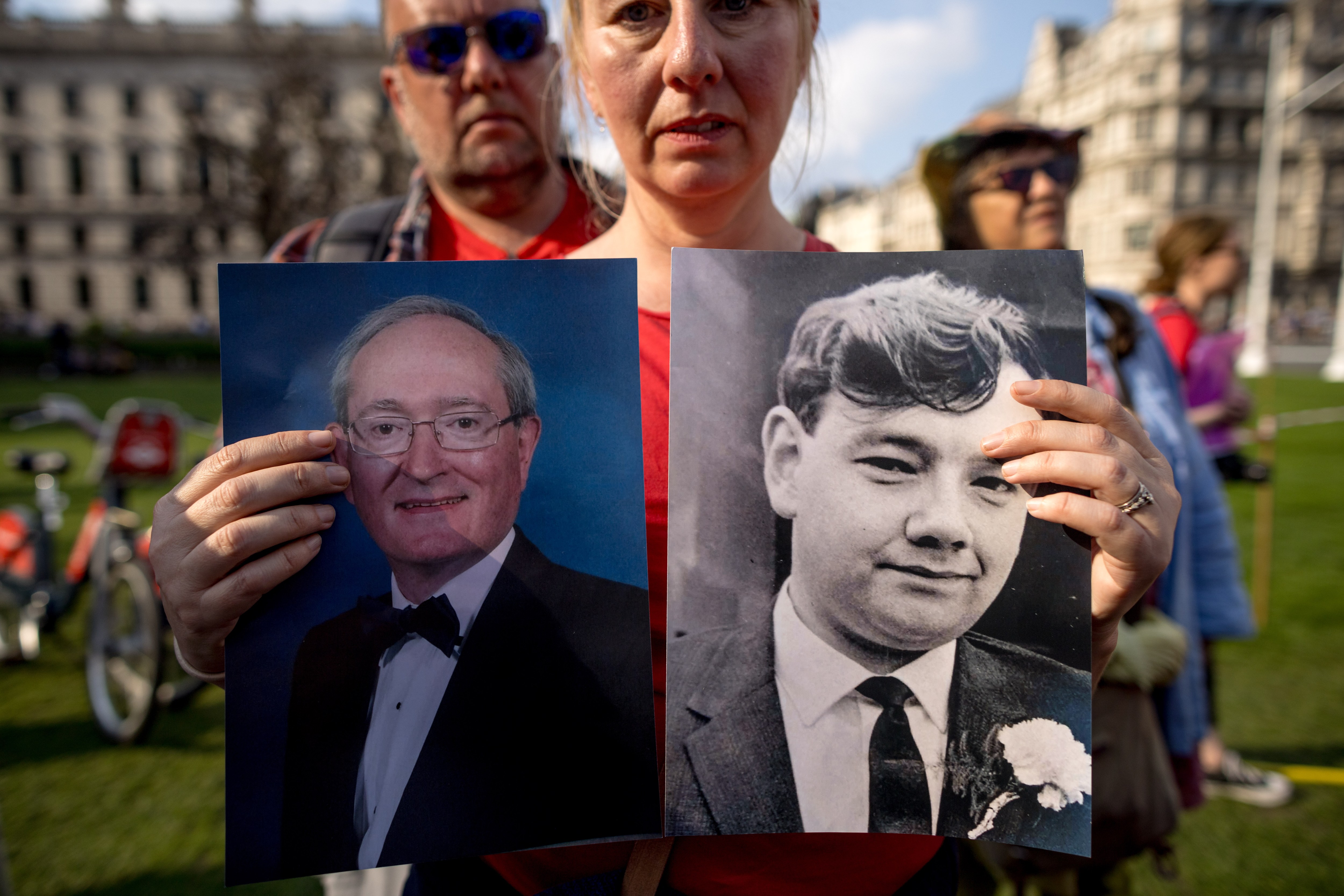 At a vigil outside parliament last week, Toni Poole holds up pictures of her father Anthony Higgs and her step-father Tony Owen, left. Both died after receiving infected blood