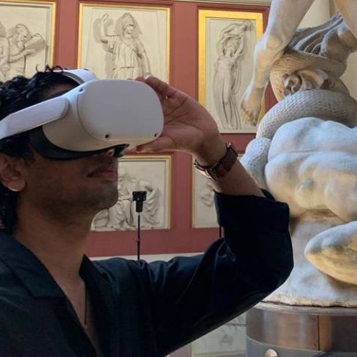 man wearing a virtual reality headset standing in an art gallery filled with classical sculptures