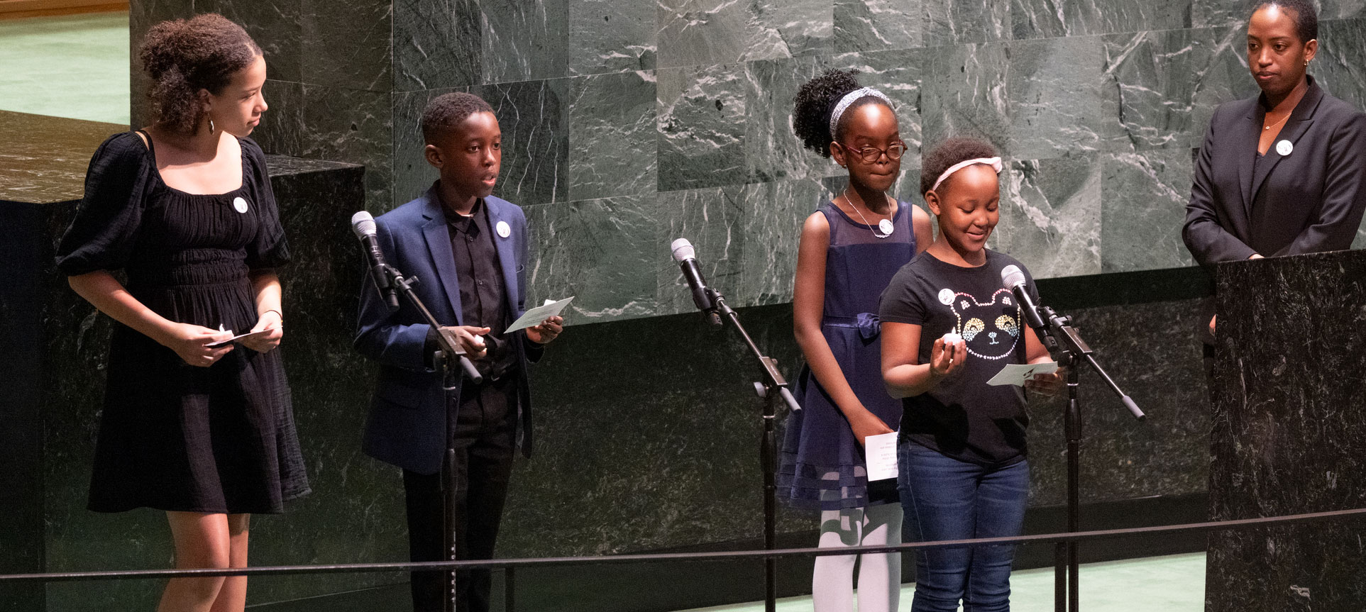 Foto de una mujer y 4 niños en el podio de la sala de la Asamblea General durante la intervención de uno de ellos