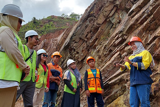 women and youths with hard hats standing among rocks