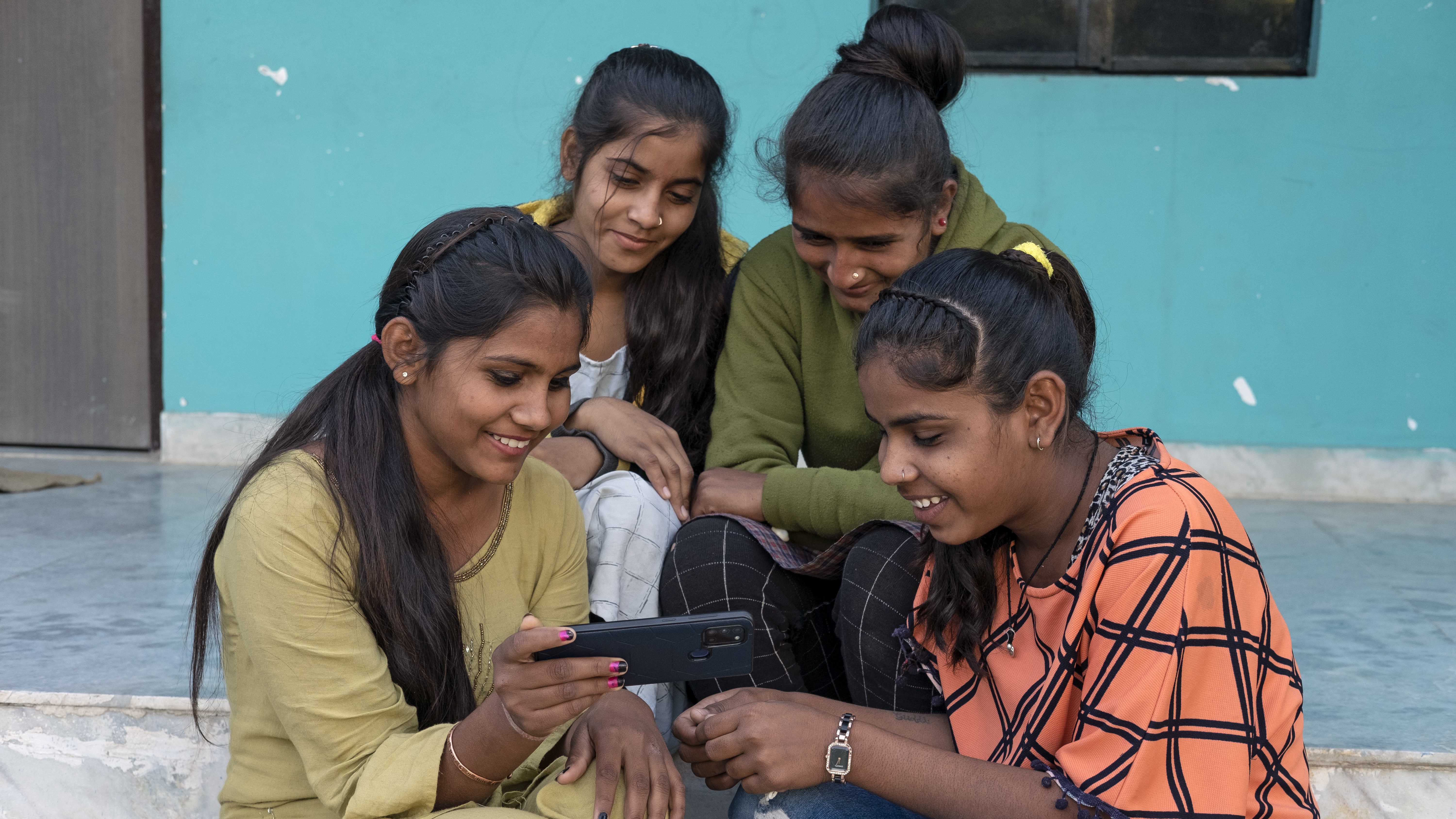 一群坐在台阶上的青春期女孩正在观看手机屏幕。
