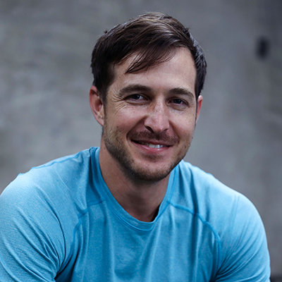 A young man in a t-shirt smiling, facing forward.