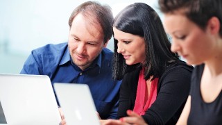 Drei junge Menschen arbeiten an ihren Laptops.