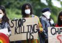 Image of protester holding poster which reads, 