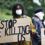 Image of protester holding poster which reads, 