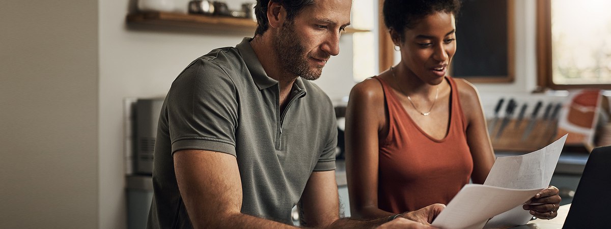 A man and a women discussing their finances in front of the laptop screen