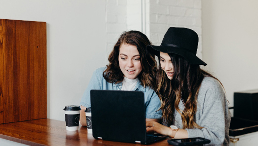 Two people smiling while using a laptop.