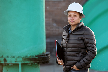 Person wearing a construction helmet while holding a tablet.