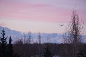 A small plane heading to the Talkeetna airport flies by the eastern flank of Denali on the evening of March 9, 2024. (Photo by Yereth Rosen/Alaska Beacon)