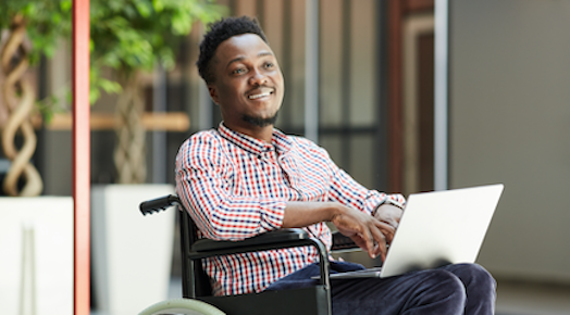 Smiling man in wheelchair with laptop