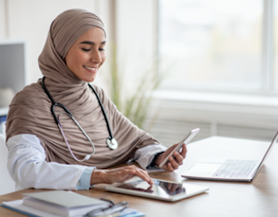 Smiling female doctor with laptop and tablets