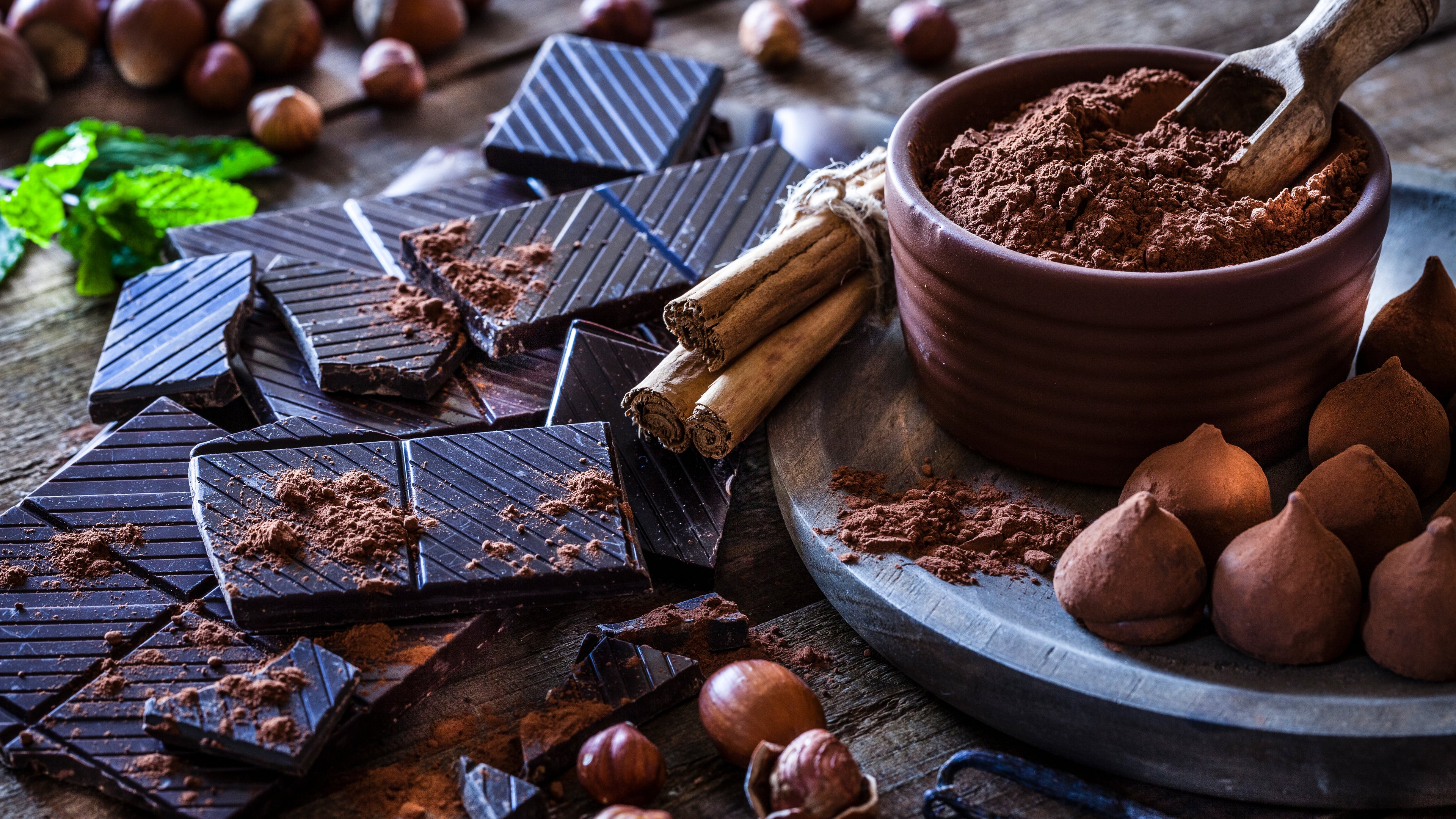 Rustic wooden table filled with ingredient for preparing homemade chocolate truffles.