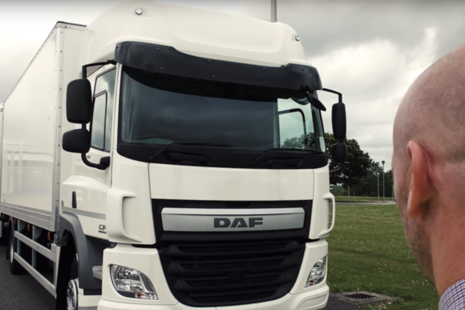 A lorry driver looking at a parked lorry as they are about to start their walkaround check