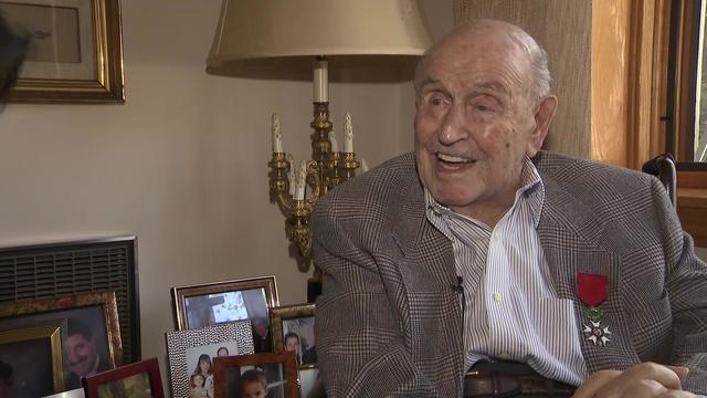 Jack Hausman sits in a chair with his French Legion of Honor medal pinned to his lapel. 