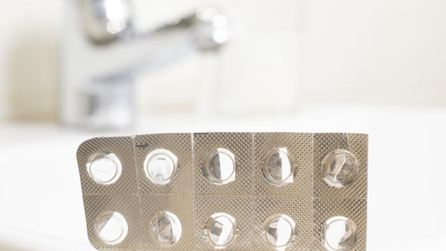 Empty packaging of  encapsulated pills on the sink of a toilet. 