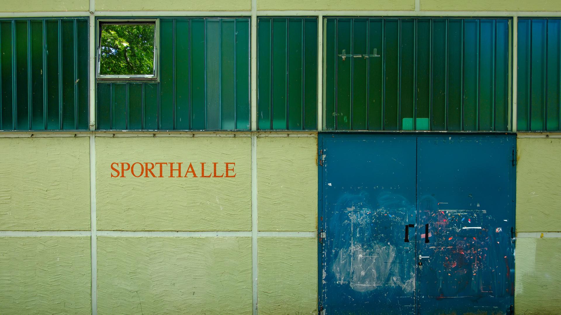 Außenaufnahme eines Gebäudes mit der Aufschrift SPORTHALLE (Symbolbild).