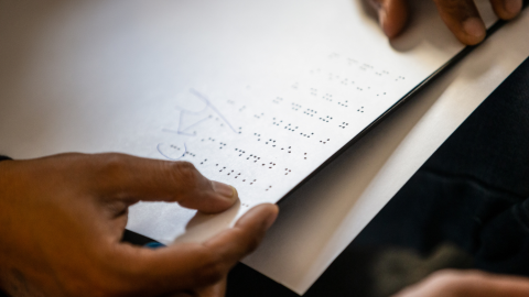 Close-up of braille sheet being read by student at a school for the blind.