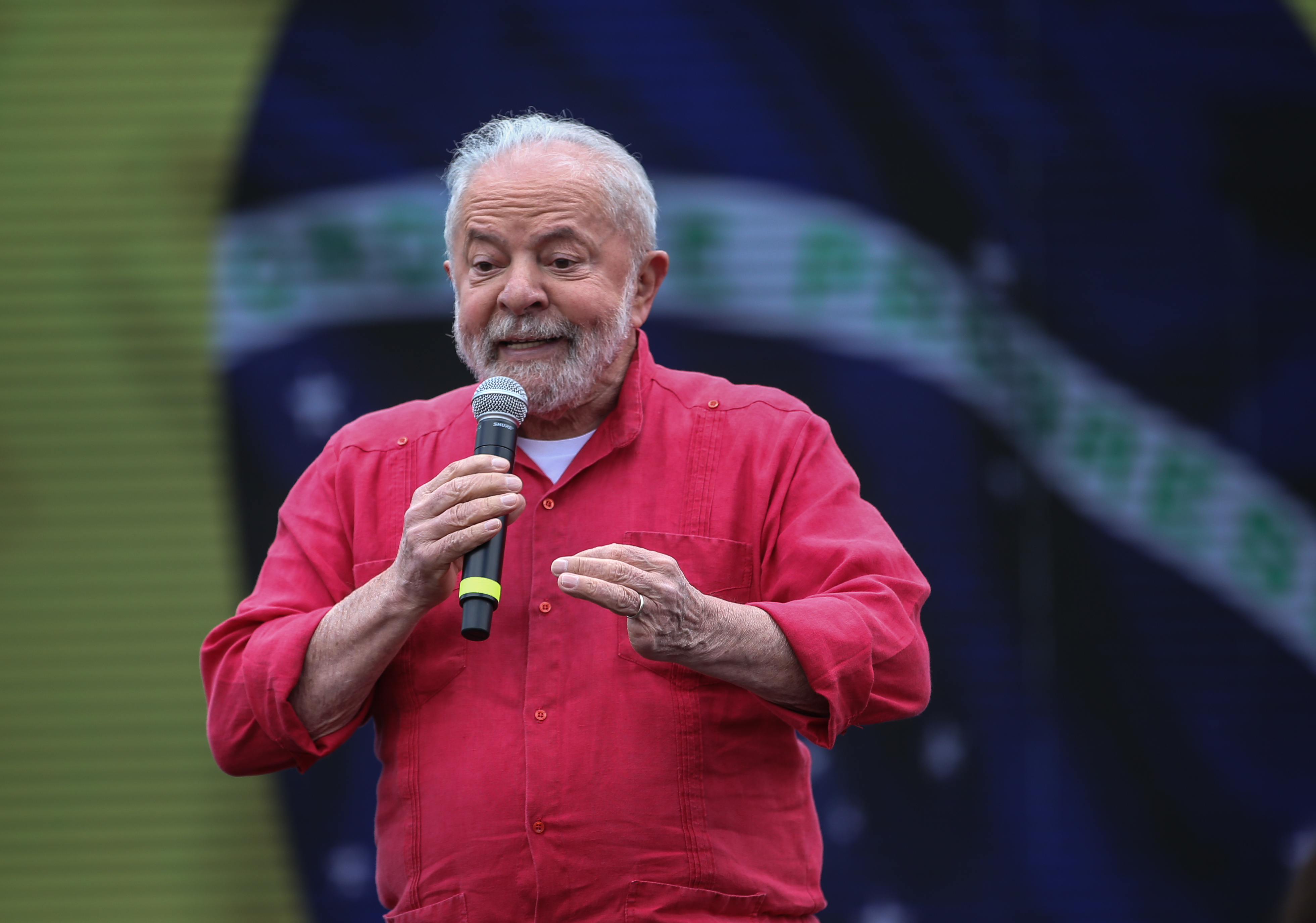 A photo of ex president Lula from Brazil speaking in front of a Brazilian flag