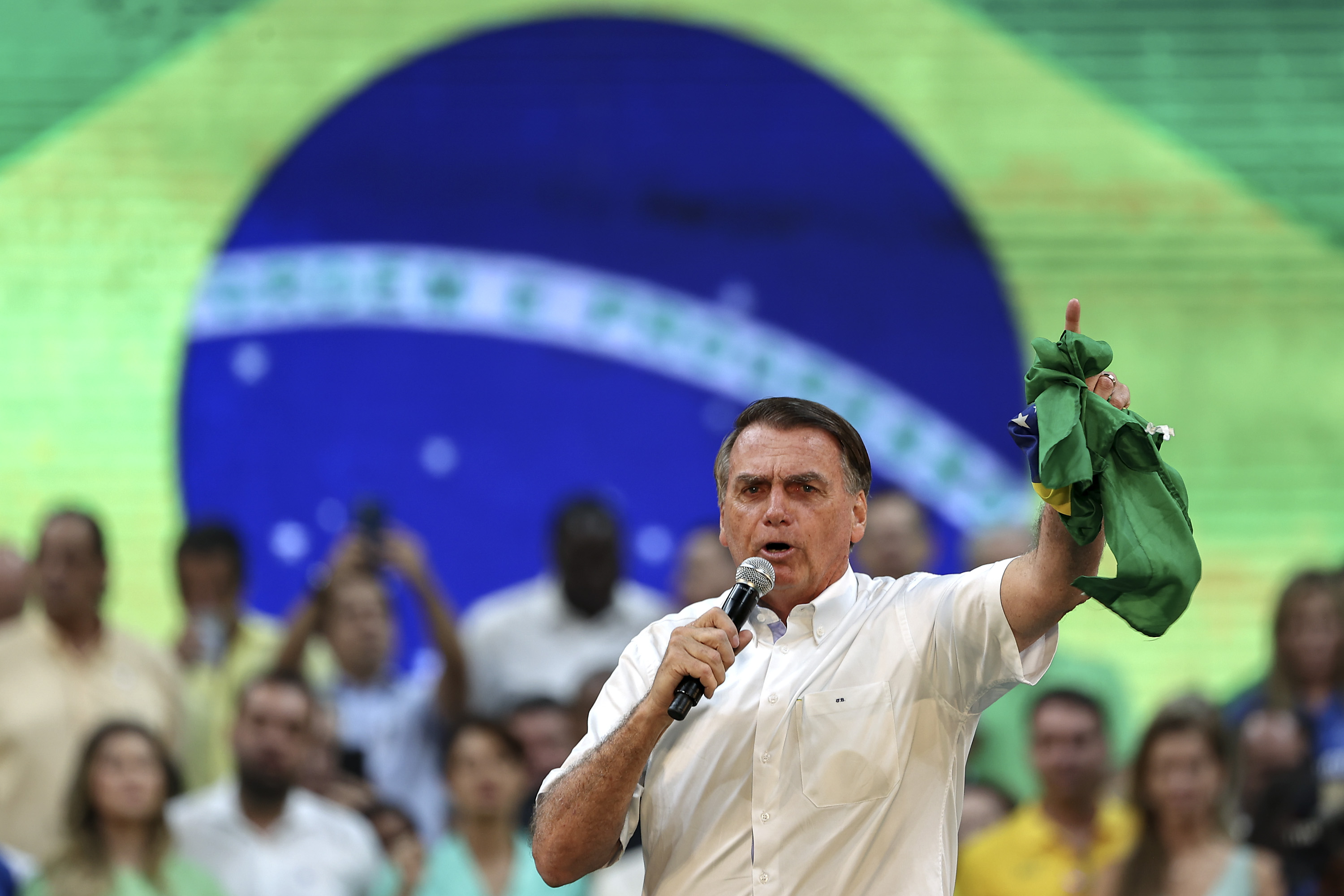 Photo of Brazil president Bolsonaro giving a public speech in front of a crowd and a Brazilian flag
