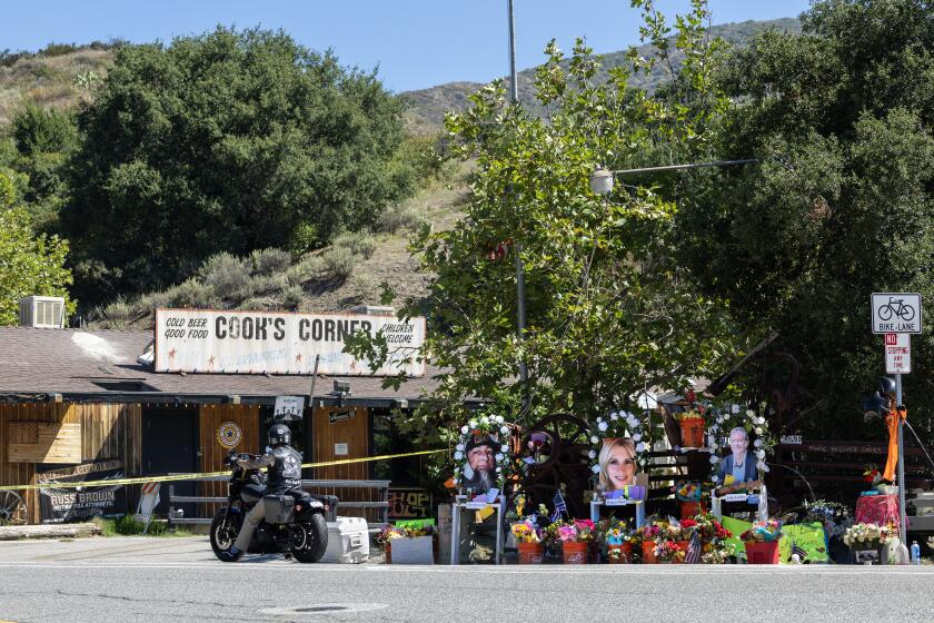 Trabuco Canyon, CA - August 29: A motorcyclist pays his respects at a growing memorial to the mass shooting victims after John Snowling, a retired Ventura police sergeant, killed three people and wounded six others at Cook's Corner in Trabuco Canyon Tuesday, Aug. 29, 2023. The shooting victims were Glen Sprowl Jr., left, 53, of Stanton, Tonya Clark, middle, 49, of Scottsdale, Ariz., and John Leehey, right, 67, of Irvine. (Allen J. Schaben / Los Angeles Times)