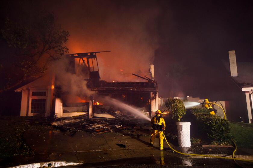 Firefighters work to contain the Saddleridge fire from spreading a home burns on Friday, October 11, 2019 in the Porter Ranch neighborhood of Los Angeles, CA. (Patrick T. Fallon/ For The Los Angeles Times)