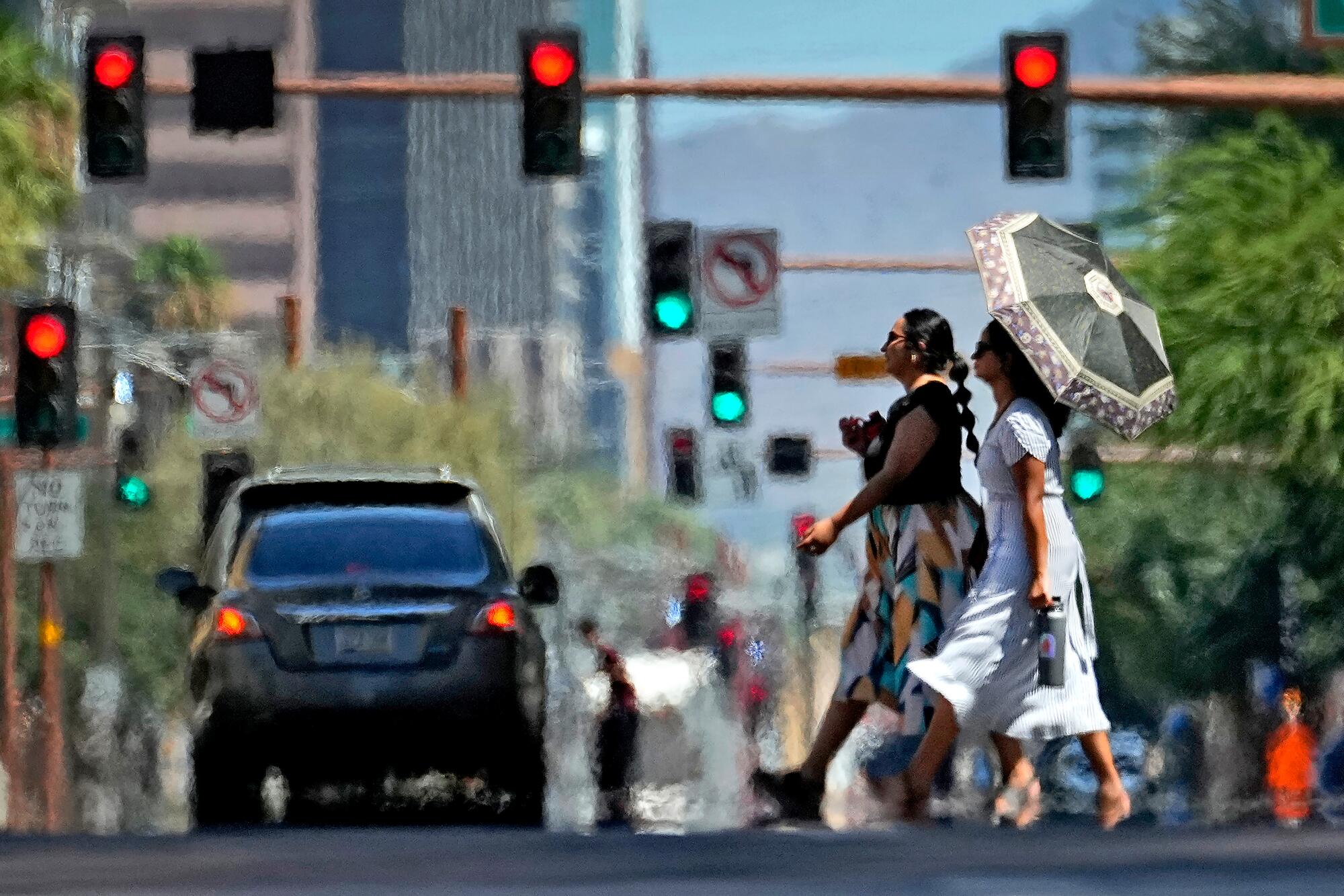 Heat ripples from hot asphalt as two women cross a street.
