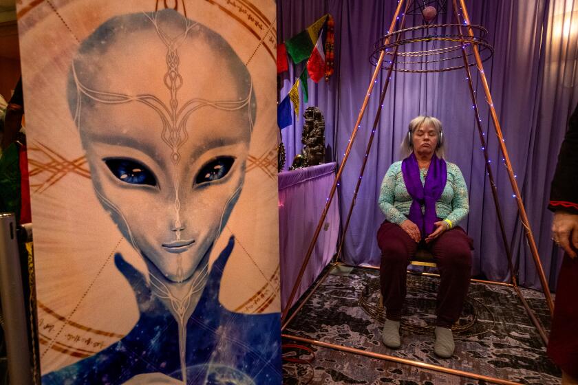 LOS ANGELES, CA-February 9, 2024: Carol Chappell, from Sedona, Arizona, sits inside a pyramid known as a multi dimensional healing chamber enhanced by tensor rings on display at the Conscious Life Expo at the LAX Hilton Hotel in Los Angeles. (Mel Melcon / Los Angeles Times)